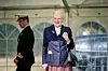 Dronning Margrethe smiler under besøg i telt ved GeoCenter Møns Klint med officer i baggrunden.