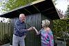 Hilda Heick og ægtefælle foran grønt haveskur med pensel mellem sig i haven.
