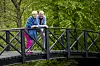 Hilda og Keld Heick står og smiler på en sort træbro i en grøn park