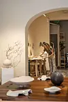 Person arbejder ved bord i keramikværksted med færdige skulpturer foran.