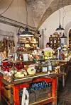Inde i en rustik delikatessebutik med ost, glas og brød bag disken