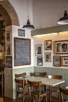 Lille café med træstole, marmorbord og menu skrevet på en stor tavle ved væggen.