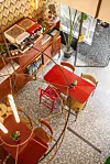 Røde caféborde og træmøbler på mosaikgulv set ovenfra