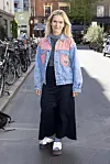 Anne Glad står i en bygade med cykler parkeret langs fortovet.