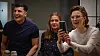 Tre personer ved et bord, hvor den ene tager et billede med en smartphone
