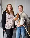 Två personer står bredvid varandra inomhus, en håller i en käpphäst.