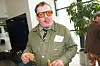 Med orange briller spiser en snack i en moderne lobby hos Strax.