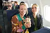 To smilende passagerer med glas mousserende vin i sæderne ombord på et fly