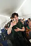 Passager står i midtergangen og skåler med et glas på et fyldt Strax-fly