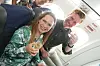 To glade flypassagerer skåler med drikkevarer i sæderne om bord på et fly