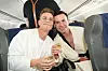 To smilende passagerer skåler med champagne i sæderne på et passagerfly