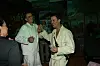De danser og taler med gæster ved en fest med tropisk bagtæppe.