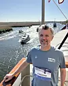 Mand i Royal Run 24 T-shirt står på dækket af et skib ved en kanal med både.