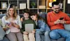 Familie på fire sidder i sofaen og bruger hver deres mobil og tablet.