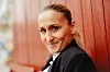 Smilende Marijana Janković læner sig op ad rød trævæg i udendørs portræt