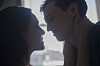 Unge par i tæt, intim silhuet ved et vindue med sløret by i baggrunden