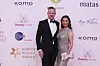 To festklædte personer poser på den røde løber foran Danish Beauty Award 2026-væg.