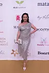 Kvinde i sølvfarvet kjole poserer på gulvtæppe foran Danish Beauty Award 2026 fotovæg.