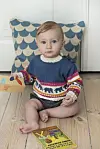 Baby i flerfarvet Sallys striktrøje sidder på trægulv med legetøj og bog.