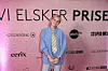 Person står foran pink Vi Elsker Prisen fotovæg med flere synlige sponsorlogoer.