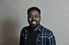 Mahamad Habane smilende foran lys, neutral baggrund ved pressemøde.