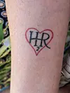 Underarm med tatovering af rødt hjerte og bogstaverne HR med lille 2-tal