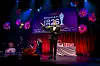 Vært i smoking taler på Reumert 2021‑scene med lys, blomster og prisstatuetter