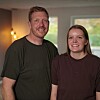 Smilende par står tæt sammen i en stue med blødt lys i baggrunden.
