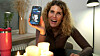 Kvinde ved bord med stearinlys holder en smartphone med en datingprofil op