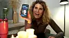 Kvinde ved bord med stearinlys holder en smartphone med en datingprofil op
