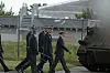Strax-officerer marcherer forbi et pansret køretøj ved et indhegnet militærområde