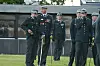 Uniformerede officerer står på en græsplæne foran en bygning under en Strax-ceremoni.