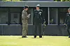 To officerer i uniform taler sammen på græsplæne foran lav militær bygning