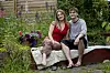Sofie Sytnik Jørgensen og Laurids Bihl sidder tæt sammen på en bænk i en farverig have.
