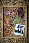 Trærangle med tørrede blomster og et polaroid-foto nederst til højre