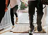 To børn med rygsække træder ind ad en solbelyst hoveddør efter skole.