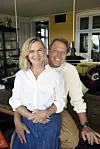 Mikkel Beha og Marian Midé sidder sammen i en stue og smiler til kameraet.