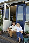Mikkel Beha og Marian Midé sidder på en trappe foran deres hus. De smiler og ser glade ud.