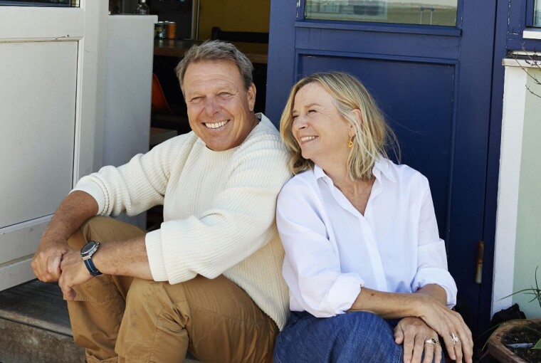 Mikkel Beha og Marian Midé sidder på en trappe foran deres hus. De smiler og ser glade ud.