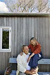 Mikkel Beha og Marian Mid-e sidder op af en trævæg og griner.