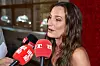 Kvinde fra Bachelorette 2026-finale interviewes af medier med røde mikrofoner.