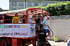 Unge mennesker står på rød lastbil med banner under demonstration i solskin