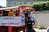 Unge mennesker står på rød lastbil med banner under demonstration i solskin