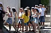 Gruppe unge med hvide studenterhuer går sammen udendørs i solskin