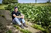Ung mand sidder på jordsti mellem grønne afgrøder på marken