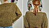 Ryggen af person i olivengrøn, håndstrikket sweater foran væg med facetteret spejl.