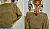 Ryggen af person i olivengrøn, håndstrikket sweater foran væg med facetteret spejl.