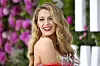 Blake Lively smiler på rød løber foran en blomsterbaggrund i London