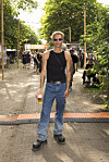 Person står med øl på festivalsti omgivet af træer og andre gæster på Roskilde Festival.