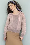 Kvinde i lyserød striksweater og beige nederdel står foran lys blågrøn væg
